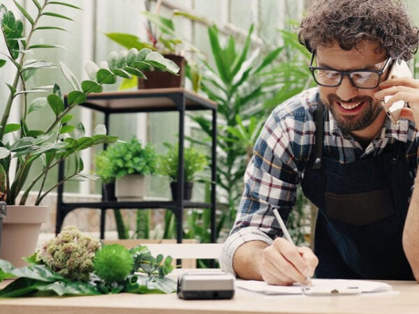 Smiling man working with POS system in greenhouse environment.