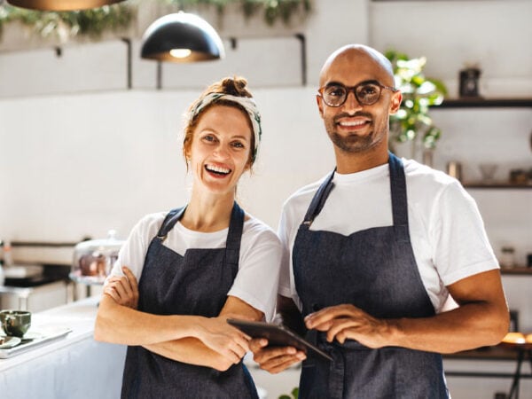 Happy restaurant staff with tablets in a modern restaurant setting.