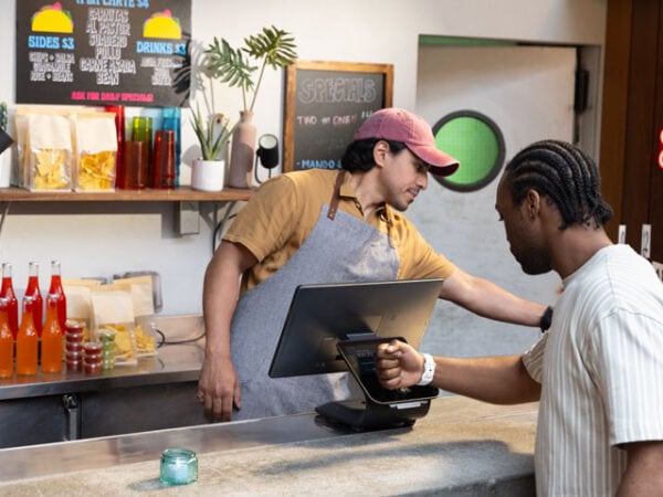 Customer paying with card at fast food counter with employee.