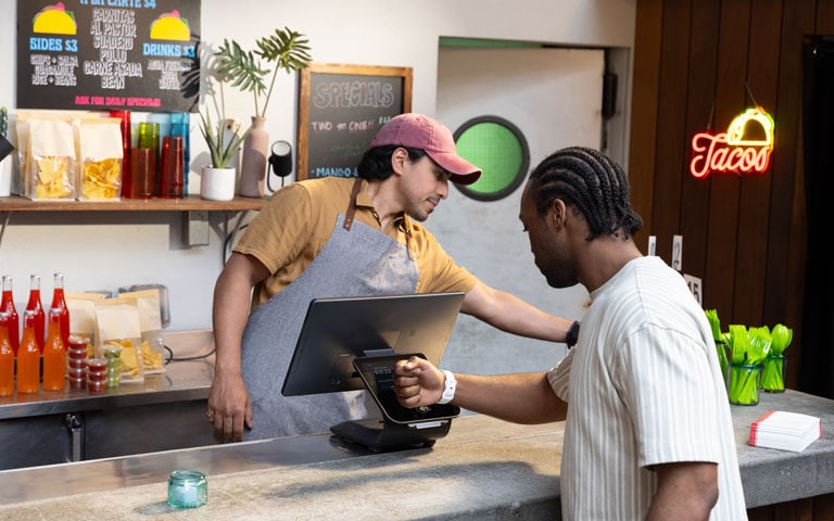 Customer paying with card at fast food counter with employee.