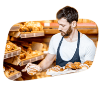 Bakery employee selecting fresh bread in a bakery shop.