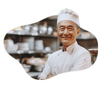 Happy chef in a professional kitchen with cooking utensils and ingredients.
